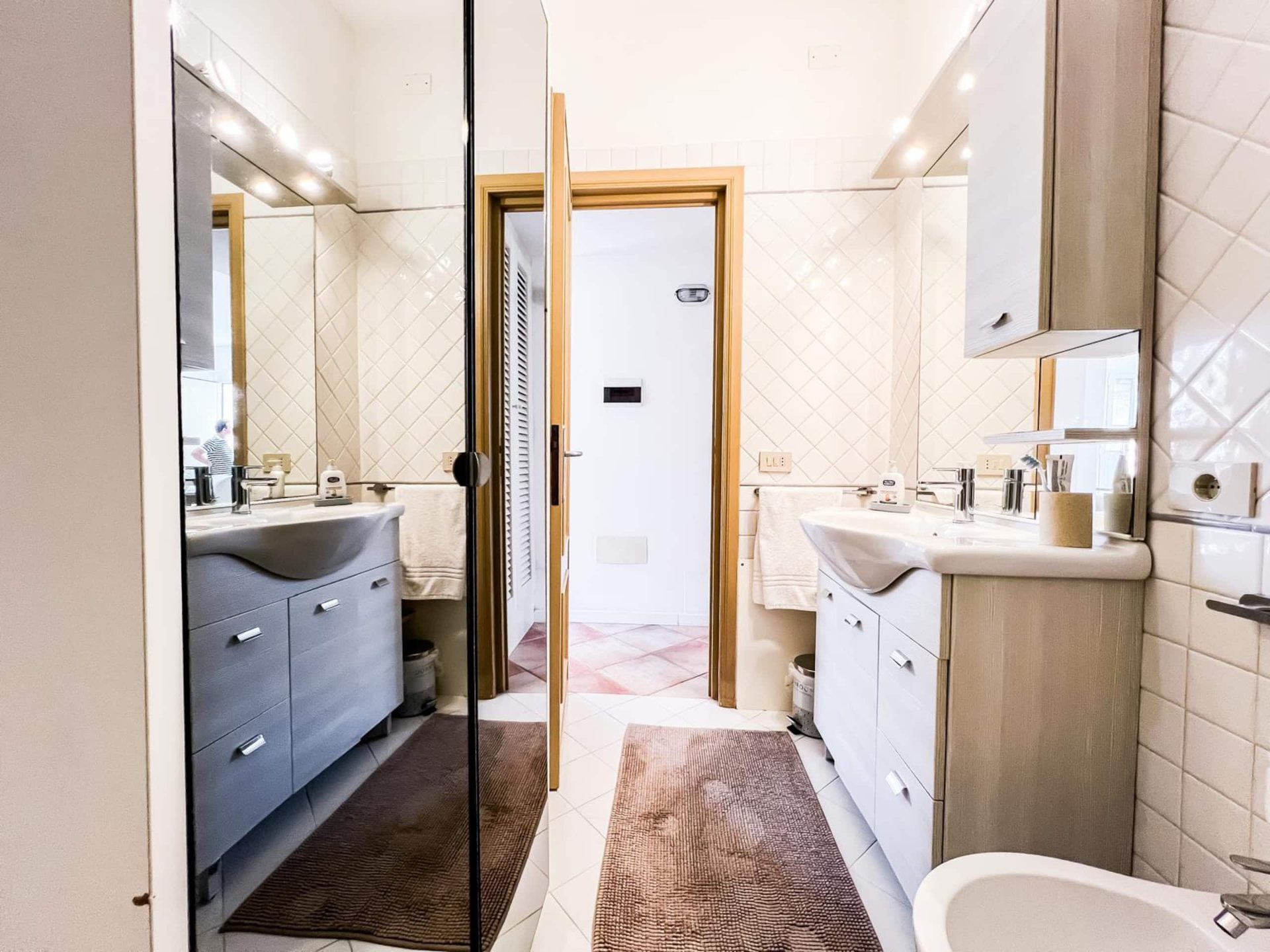 Il bagno con il lavabo sul mobile in legno, la parete a specchio a tutta altezza e il bidet