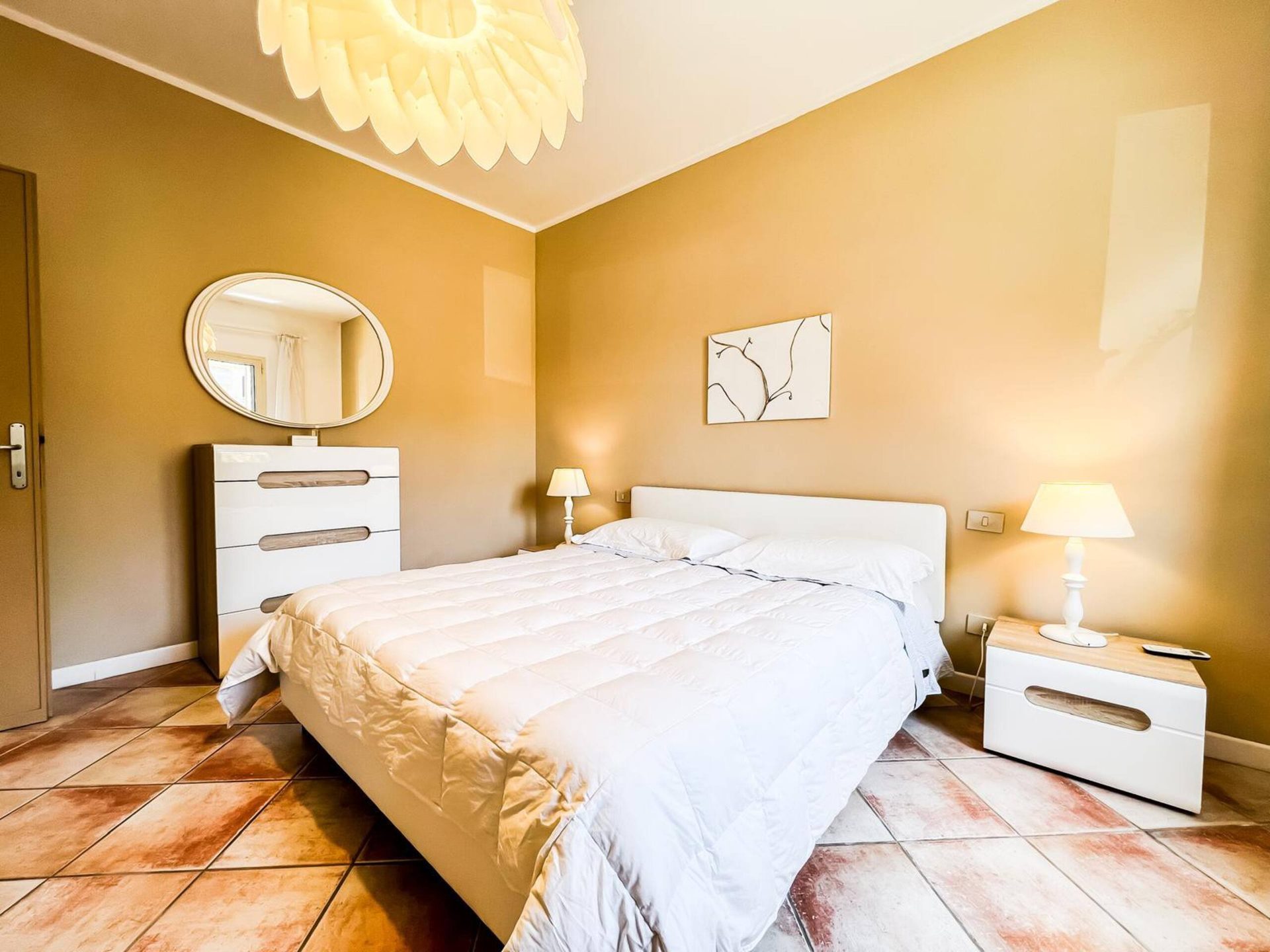 La camera da letto con lo specchio ovale sopra il comò bianco