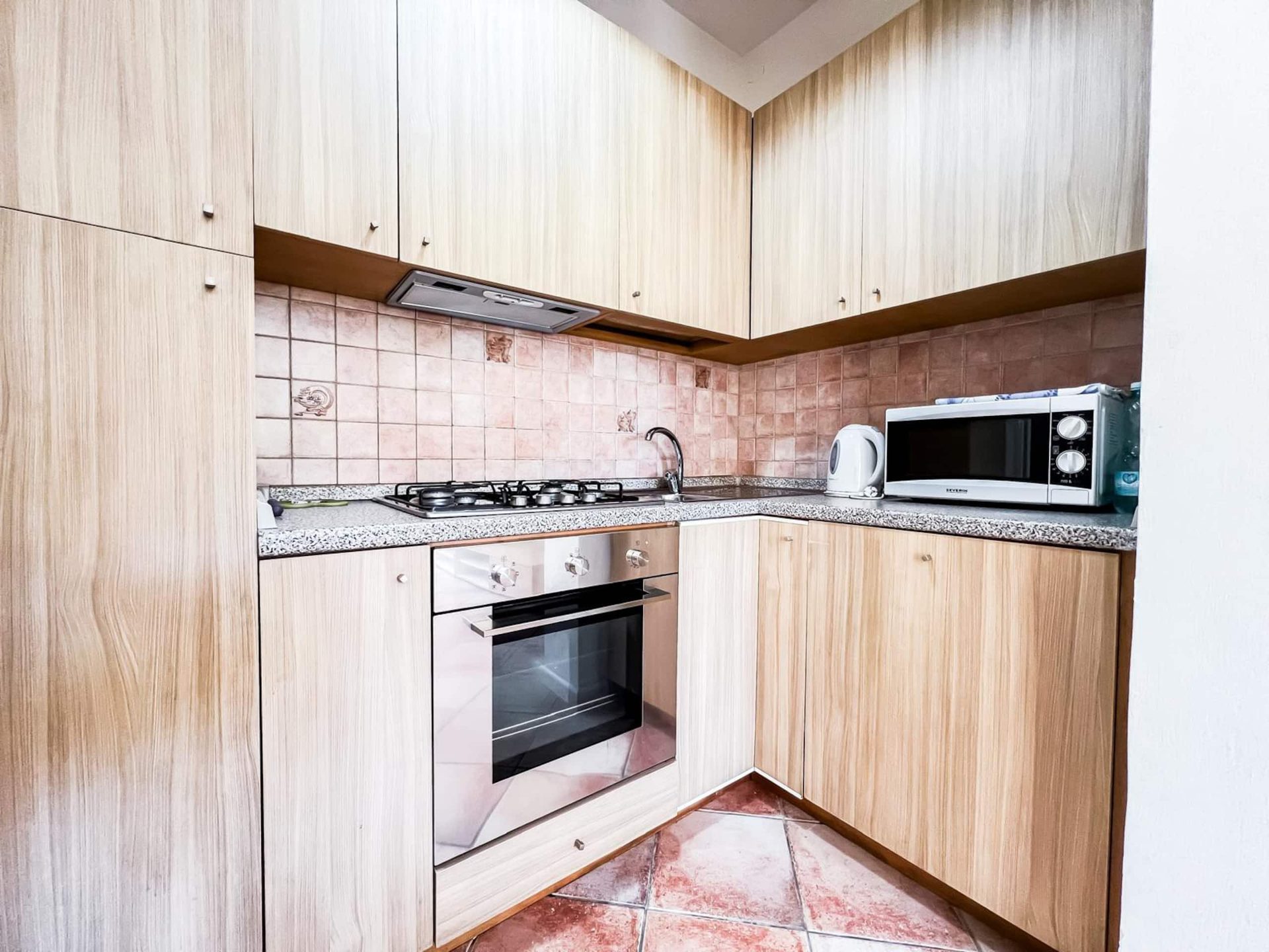 La cucina separata ad angolo con forno, fornelli a gas, forno a microonde e bollitore