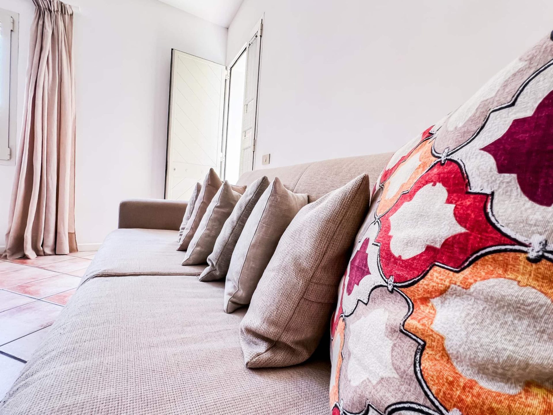 Il divano del soggiorno, che si apre in divano letto, con i cuscini beige e uno a fiori
